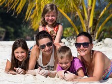 度假趴在沙滩上晒太阳的幸福家庭图片