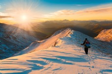 雪山朝太阳攀登的男人图片