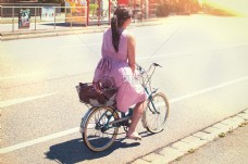 自在城市女性在紫色长裙骑在自行车城市道路