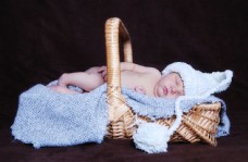 篮子里戴着帽子熟睡的新生宝宝图片